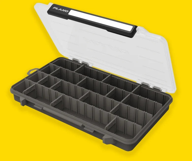 An open Plano organiser case with a clear hinged lid and a dark grey compartmentalised base, shown on a solid yellow background.